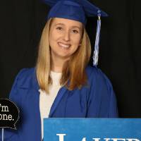 student in cap and gown with props